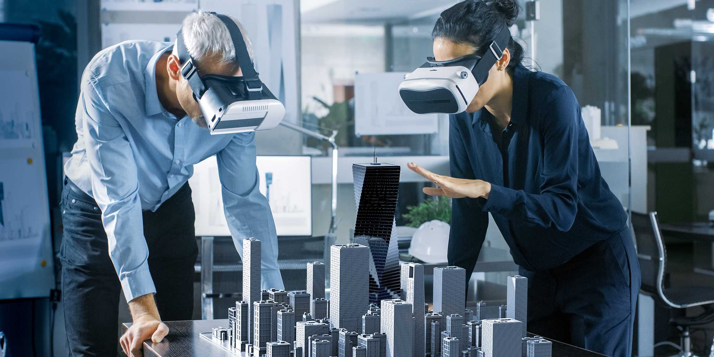 Two people using VR goggles in a dramatic way in an office.